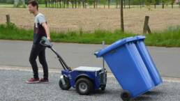 Remolcador M9 moviendo unos cubos de basura azules en la calle