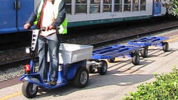 Tractor electrico hombre a bordo JACK arrastrando carritos en estacion de tren