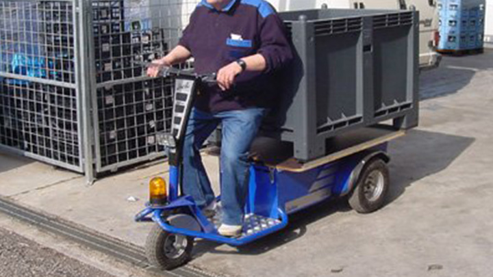 Tractor electrico hombre a bordo JACK L transportando un contenedor plático