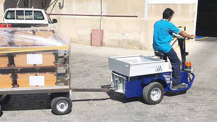 Tractor electrico para almacenes JACK MASTER con un remolque en una calle